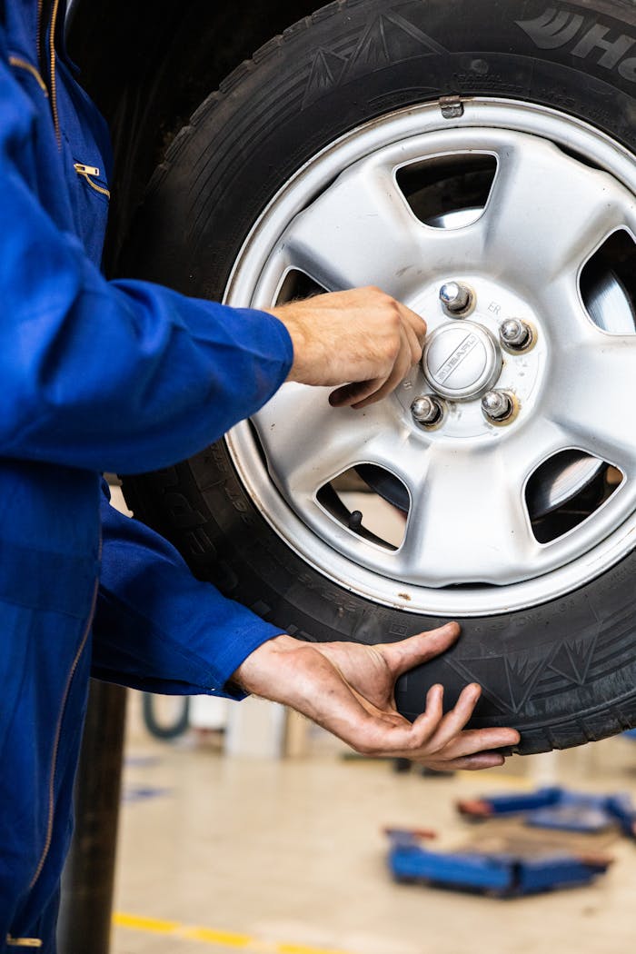 A mechanic tightens bolts on a car wheel in a professional garage setting.